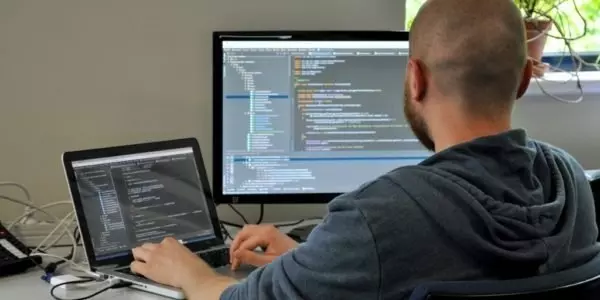Desenvolvedor de software programando em múltiplas telas. Dicas de sensibilidade cultural para programadores brasileiros que trabalham em equipes globais.